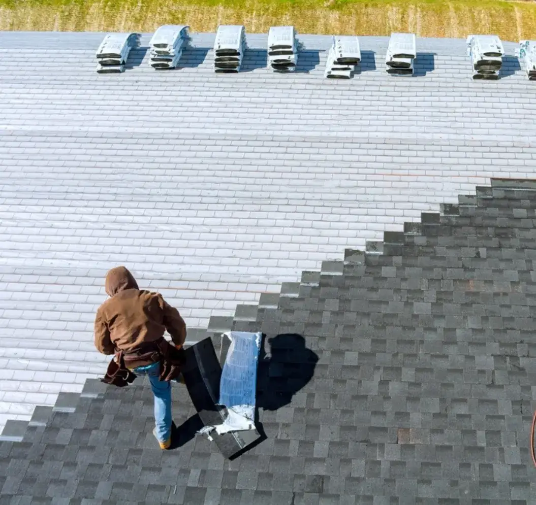 Roofer installing asphalt shingles on a residential roof.