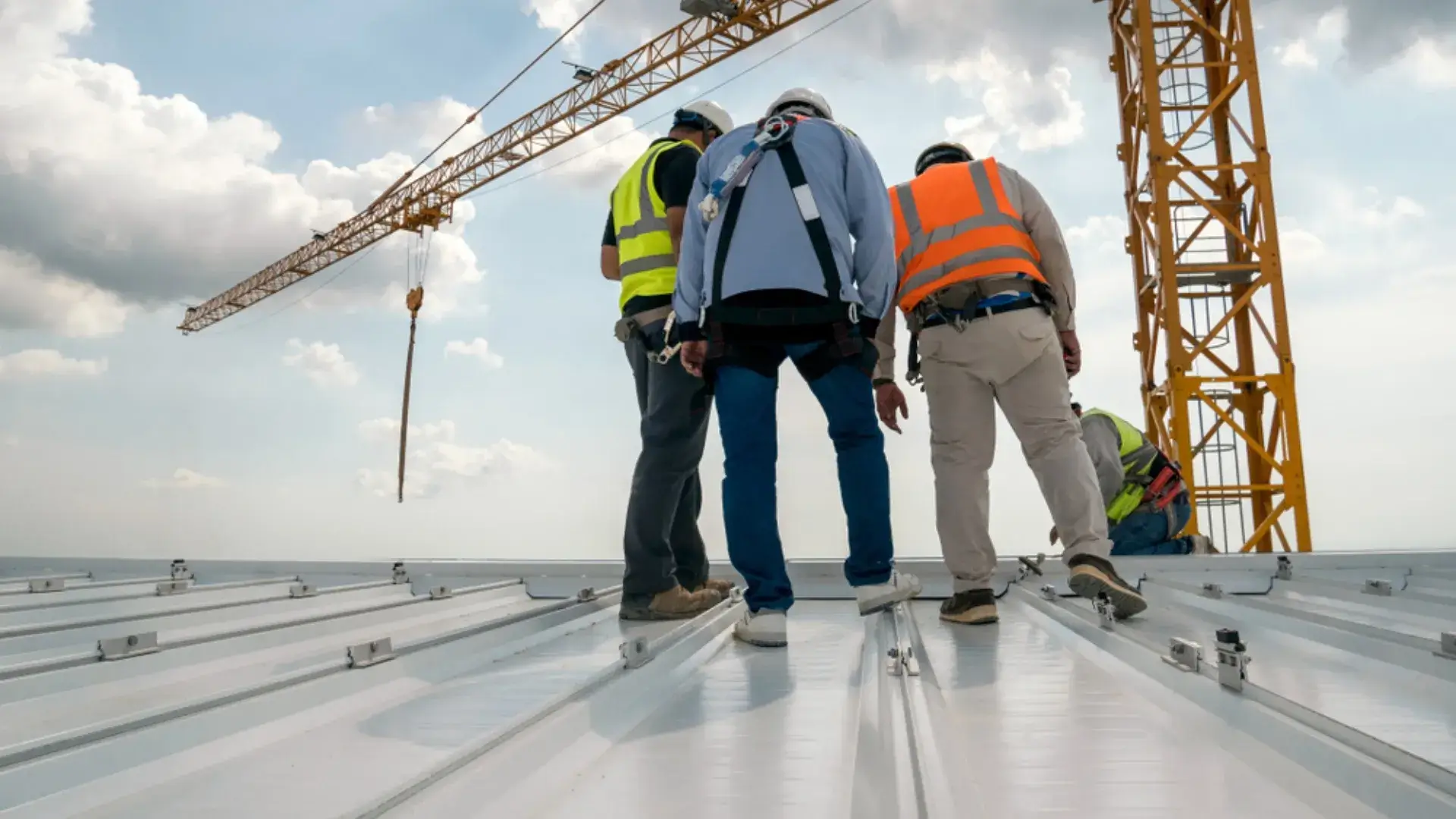 Construction workers inspecting a metal roof installation on a commercial building site.