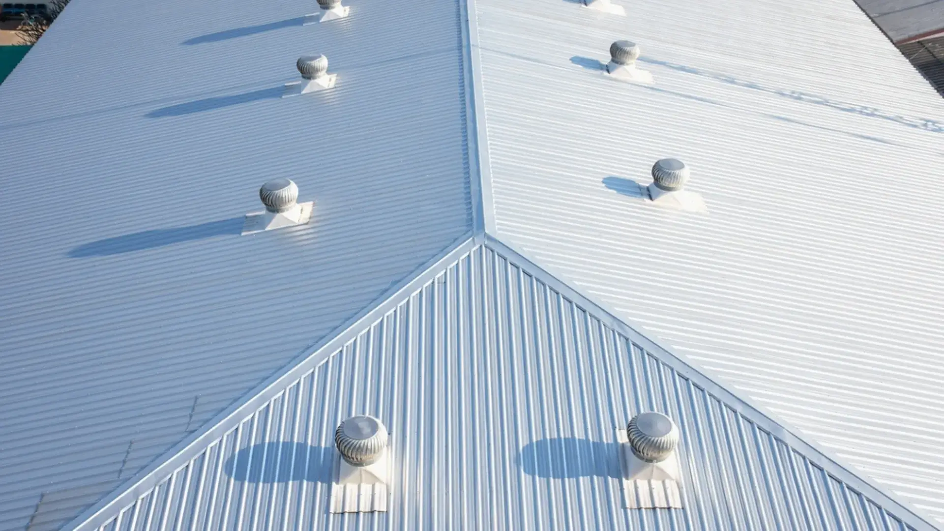 Aerial view of a metal commercial roof with ventilation turbines.