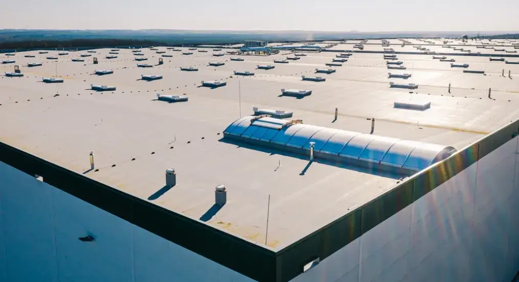 Aerial view of a large industrial flat roof with multiple skylights and ventilation systems.