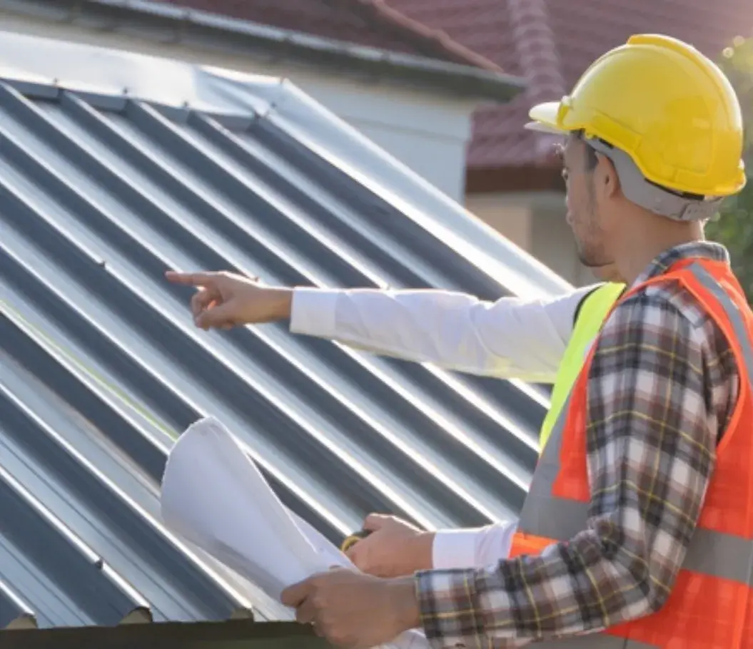 Construction worker and inspector examining a newly installed metal roof.