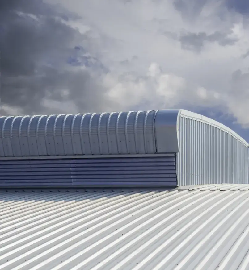 White corrugated metal roof of an industrial building with a curved ventilation system.