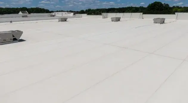 Large commercial building with a white TPO roofing system under a clear blue sky.