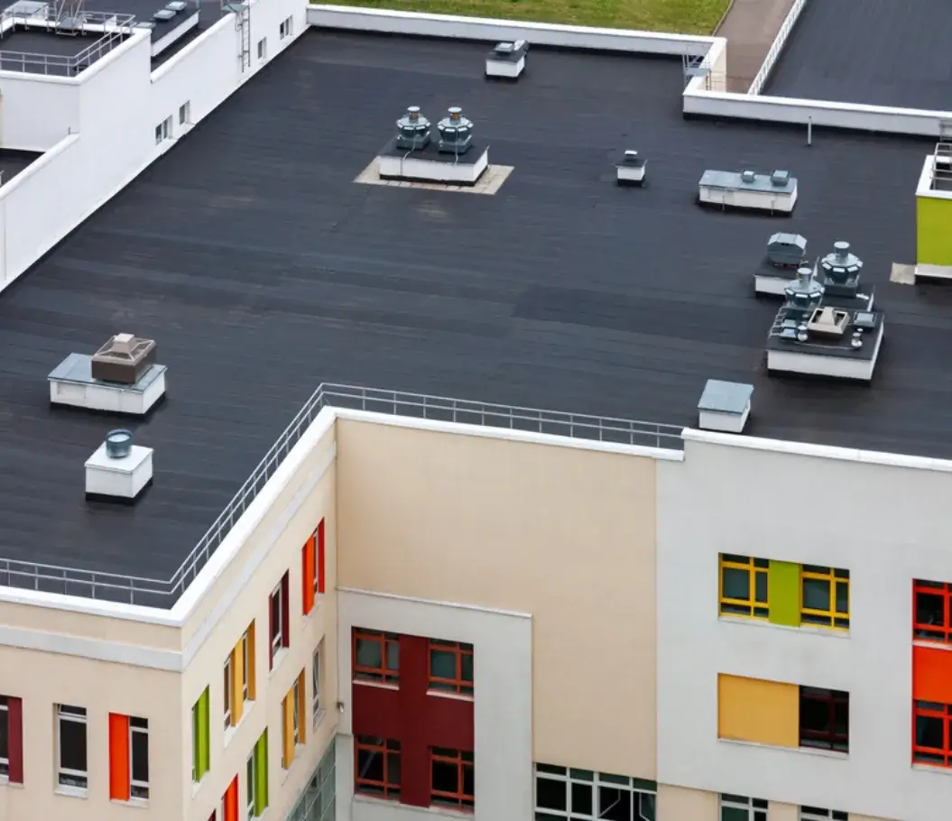 Modern commercial building with a black flat roof and HVAC systems.